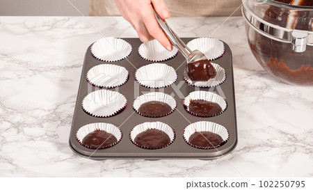 Step by step. Baking chocolate cupcakes. Scooping chocolate cupcake batter into a cupcake pan. Step by step. Baking chocolate cupcakes. Scooping chocolate cupcake batter into a cupcake pan. 102250795