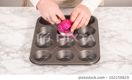 Step by step. Baking chocolate cupcakes. Lining metal cupcake pan with foil cupcake liners. 102250829