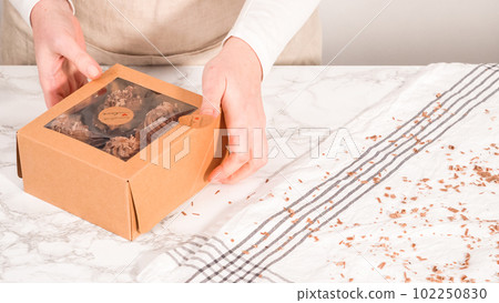 Step by step. Packaging chocolate cupcakes with chocolate ganache frosting into a paper cupcake box. Step by step. Packaging chocolate cupcakes with chocolate ganache frosting into a paper cupcake box. 102250830