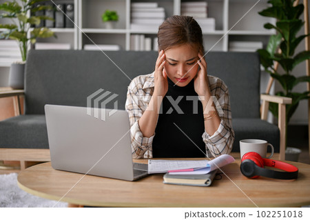 Stressed young Asian female college student preparing for the exam in her living room. Stressed young Asian female college student preparing for the exam in her living room. 102251018