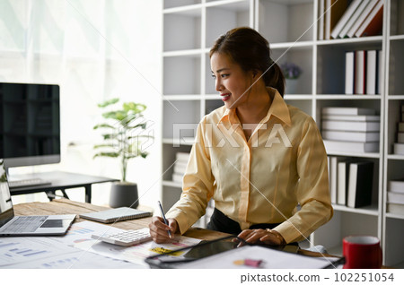 A female accountant working in her office, reviewing accounting sales reports. 102251054