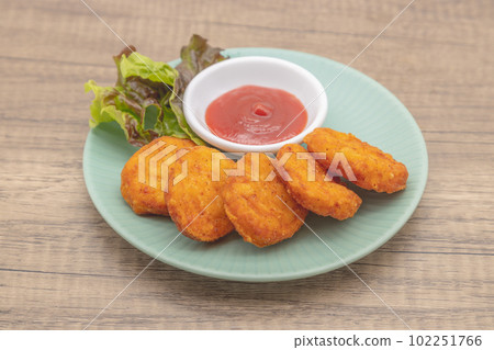 Chicken nuggets and ketchup are served on a blue plate Chicken nuggets and ketchup are served on a blue plate 102251766