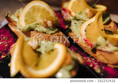 Macro photo of bruschetta with guacamole and shrimps. Delicious food in restaurant Macro photo of bruschetta with guacamole and shrimps. Delicious food in restaurant 102252418