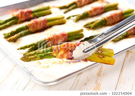 fried green asparagus wrapped in bacon close up. close-up of Bacon wrapped green asparagus bundles cooked on grill. fried green asparagus wrapped in bacon close up. close-up of Bacon wrapped green asparagus bundles cooked on grill. 102254004