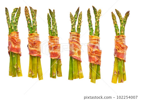 baked bundle of green asparagus wrapped in bacon isolated on a white background. 102254007