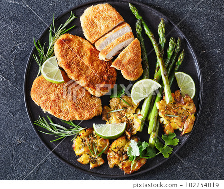 fried chicken breasts with asparagus and potatoes 102254019
