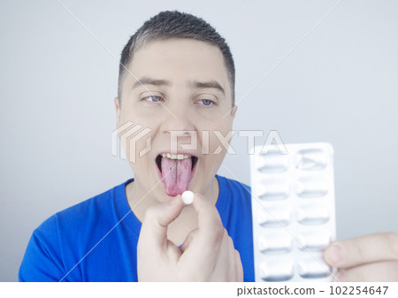 Oral probiotics. A man puts a pill with beneficial bacteria on his tongue. Dysbacteriosis and imbalance of beneficial and harmful microorganisms in the mouth. Increase immunity and improve health. 102254647