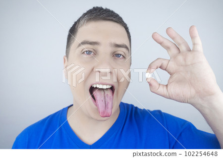 Oral probiotics. A man puts a pill with beneficial bacteria on his tongue. Dysbacteriosis and imbalance of beneficial and harmful microorganisms in the mouth. Increase immunity and improve health. 102254648