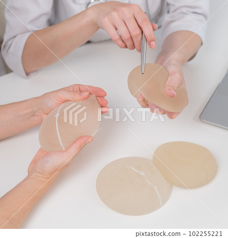 Caucasian woman and plastic surgeon touching and choosing breast implants. Caucasian woman and plastic surgeon touching and choosing breast implants. 102255221