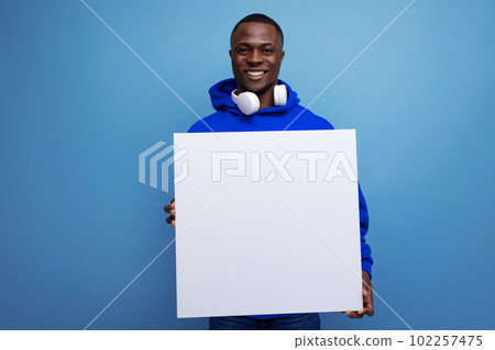 handsome young african man showing a white board with a mockup for advertising on the background 102257475