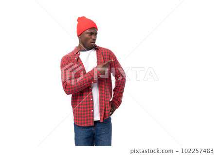 portrait of 30s black american man dressed in red shirt and cap pointing to the side on white studio portrait of 30s black american man dressed in red shirt and cap pointing to the side on white studio 102257483