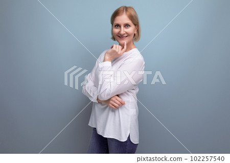 positive blond middle aged woman in white blouse on studio background 102257540