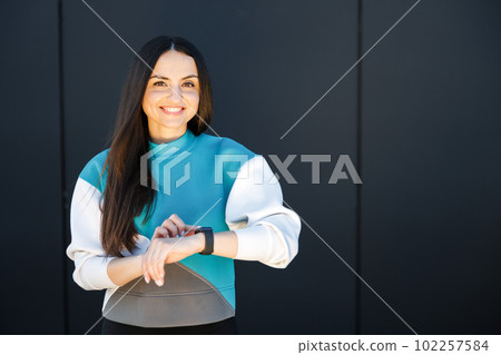 Woman uses a smart watch to measure the pulse on the hands. A woman does sports on the street. Fitness and a healthy lifestyle 102257584