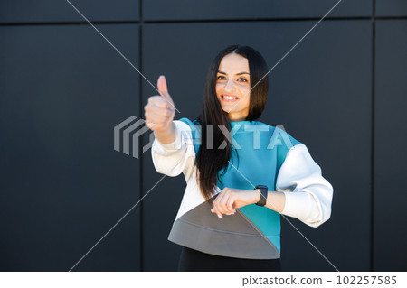 Cute sporty girl smiling cutely and showing good job gesture while standing outside during training. 102257585
