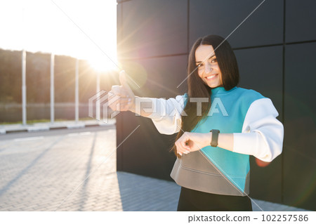 Cute sporty girl smiling cutely and showing good job gesture while standing outside during training. 102257586