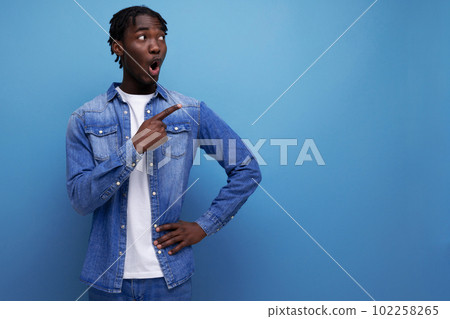 surprised stylish american young man with dreadlocks with a brilliant idea shows to the side surprised stylish american young man with dreadlocks with a brilliant idea shows to the side 102258265