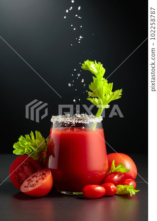 Sea salt is poured into a glass of tomato juice with celery. Sea salt is poured into a glass of tomato juice with celery. 102258787