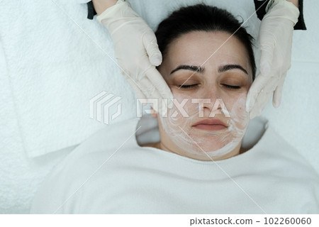 Cosmetologist cleaning woman's face before applying face treatments Cosmetologist cleaning woman's face before applying face treatments 102260060