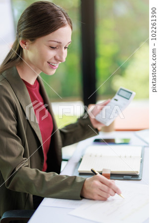 Concept of business office woman working,Businesswoman smile while working about her invesment plan with analyzing document and business investment graph data by using laptop on desk in workstation. 102261390