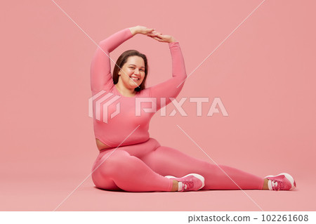 Self-care and well being. Young overweight woman training in sportswear against pink studio background Self-care and well being. Young overweight woman training in sportswear against pink studio background 102261608