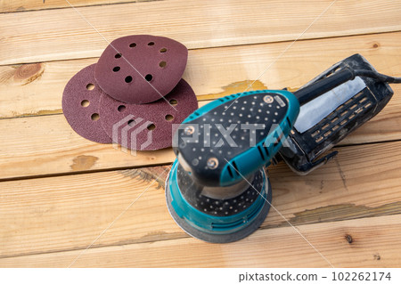 Round sandpaper discs and orbital sander. Wooden background Round sandpaper discs and orbital sander. Wooden background 102262174