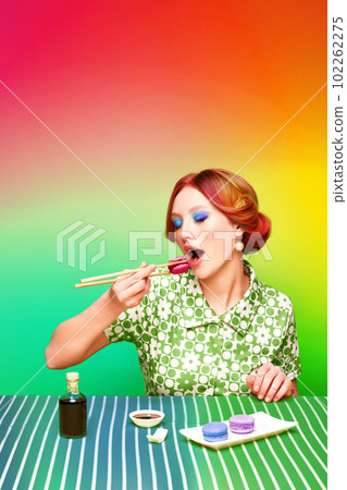 Pretty, stylish, young girl eating sweet macarons with chopsticks against gradient rainbow background. Soy sauce taste Pretty, stylish, young girl eating sweet macarons with chopsticks against gradient rainbow background. Soy sauce taste 102262275