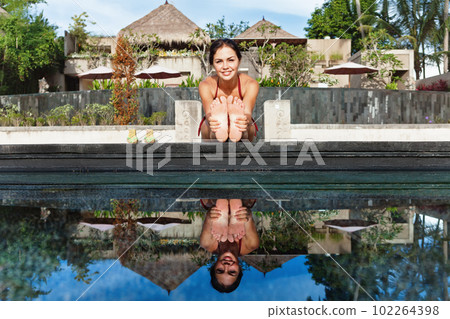 Active woman in bikini stretching at poolside to keep fit 102264398