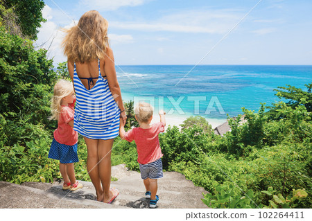 Mother, kids look at sea surf on white sand beach Mother, kids look at sea surf on white sand beach 102264411