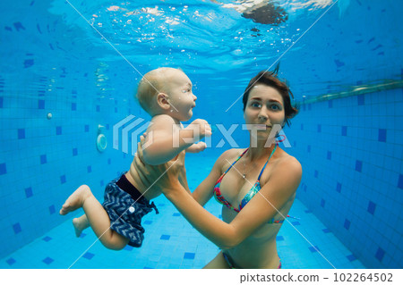 Mother with baby swimming, diving underwater in pool 102264502