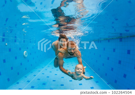 Mother, father with baby swimming, diving underwater in pool Mother, father with baby swimming, diving underwater in pool 102264504