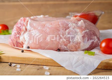 A piece of raw pork meat on a cutting board. Tomatoes, ketchup. A piece of raw pork meat on a cutting board. Tomatoes, ketchup. 102264515