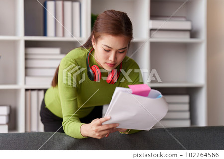 Woman sits on sofa at home, studying and analyze house bills and submitting tax forms. Woman sits on sofa at home, studying and analyze house bills and submitting tax forms. 102264566