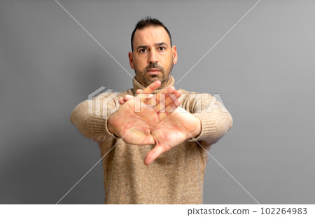 Hispanic man standing over yellow background rejection expression crossing his arms and palms making a negative sign. Hispanic man standing over yellow background rejection expression crossing his arms and palms making a negative sign. 102264983