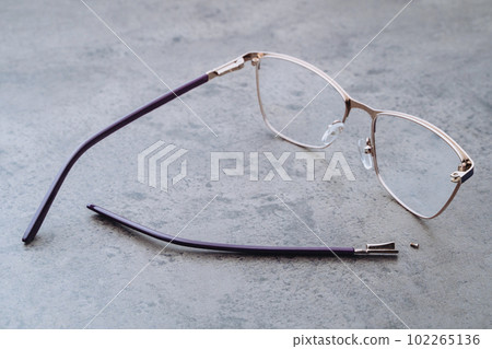 Broken eyeglasses lying on table in optical workshop Broken eyeglasses lying on table in optical workshop 102265136