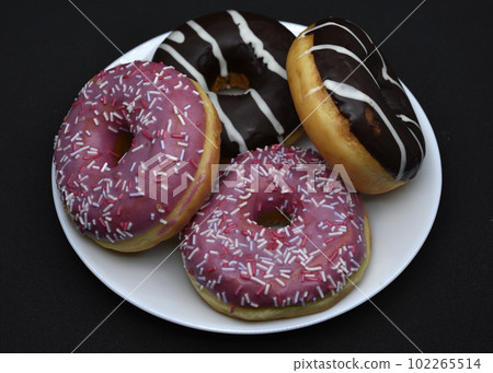 Delicious sweet donuts on a plate. Glazed doughnuts. 102265514