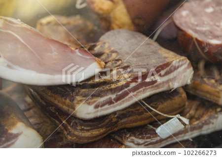 Smoked ham with cured bacon. Hams and bacon are ready for sale at the market. There are labels on them Smoked ham with cured bacon. Hams and bacon are ready for sale at the market. There are labels on them 102266273