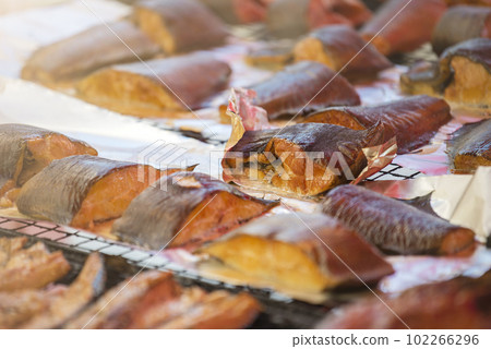 Hot smoked salmon. Large pieces of Atlantic salmon are smoked on a smokehouse grate close-up. Fish smoking plant. Hot smoked salmon. Large pieces of Atlantic salmon are smoked on a smokehouse grate close-up. Fish smoking plant. 102266296