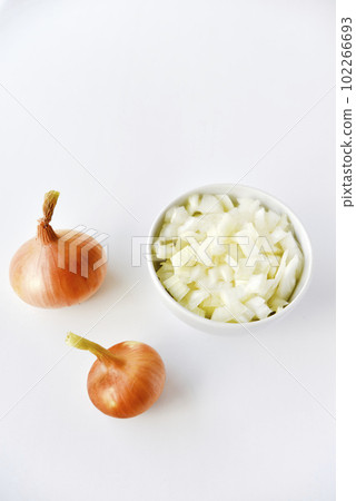 Two onions and chopped onion on a white plate. Onion on a white background. Two onions and chopped onion on a white plate. Onion on a white background. 102266693