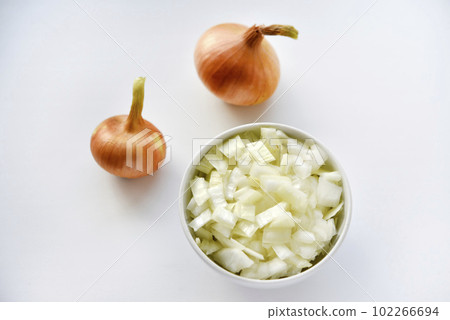 Two onions and chopped onion on a white plate. Onion on a white background. Two onions and chopped onion on a white plate. Onion on a white background. 102266694