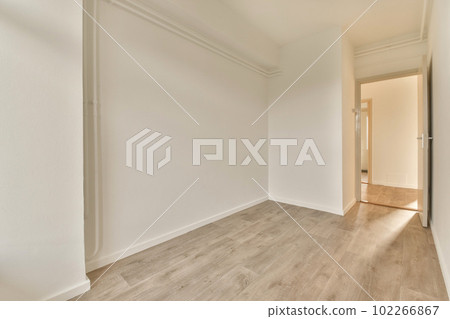 an empty room with white walls and wood flooring on the right hand side, there is a door in the left corner 102266867