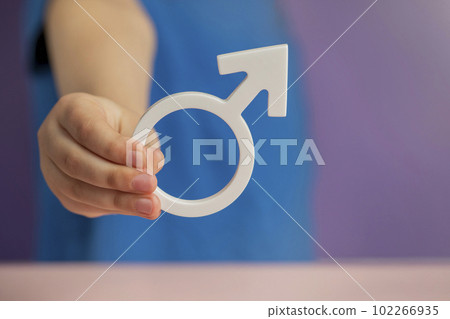 The concept of gender. Male gender symbol in hand on purple background with copy space 102266935