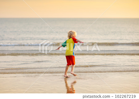 Child playing on ocean beach. Kid at sunset sea. Child playing on ocean beach. Kid at sunset sea. 102267219