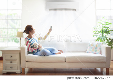 Woman with air conditioner remote control. 102267256