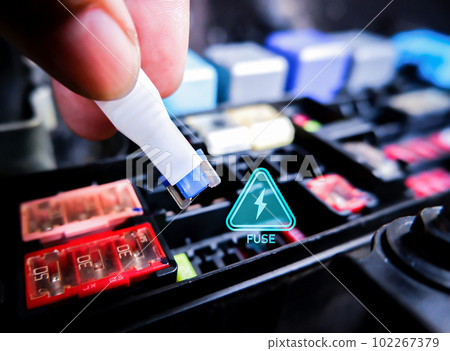 Close up of mini fuse for electric car system with a voltage caution symbol and fuse box. 102267379