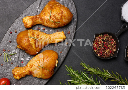 Raw chicken legs in spices on a black board, top view. Cooking with spices 102267785