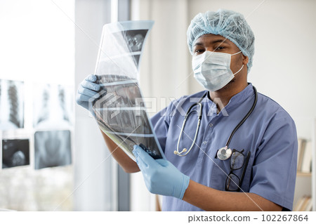 Medical practitioner holding CT scan images in exam room Medical practitioner holding CT scan images in exam room 102267864