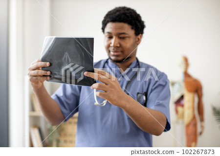 Physician in scrubs scanning X-ray image in clinic's office 102267873