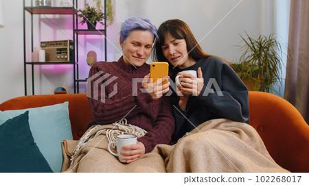 Joyful LGBTQ Duo or Friends Utilizing Smartphones for Online Browsing and Social Media Fun at Home Joyful LGBTQ Duo or Friends Utilizing Smartphones for Online Browsing and Social Media Fun at Home 102268017