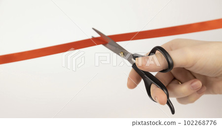 Opening of a new project. Cutting the red ribbon with scissors. Close up. 102268776