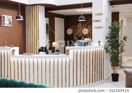 Hotel lobby with impressive design and modern furniture, expensive resort accommodation with marble floors. Empty reception front desk with computers and service bell, registration. 102269419